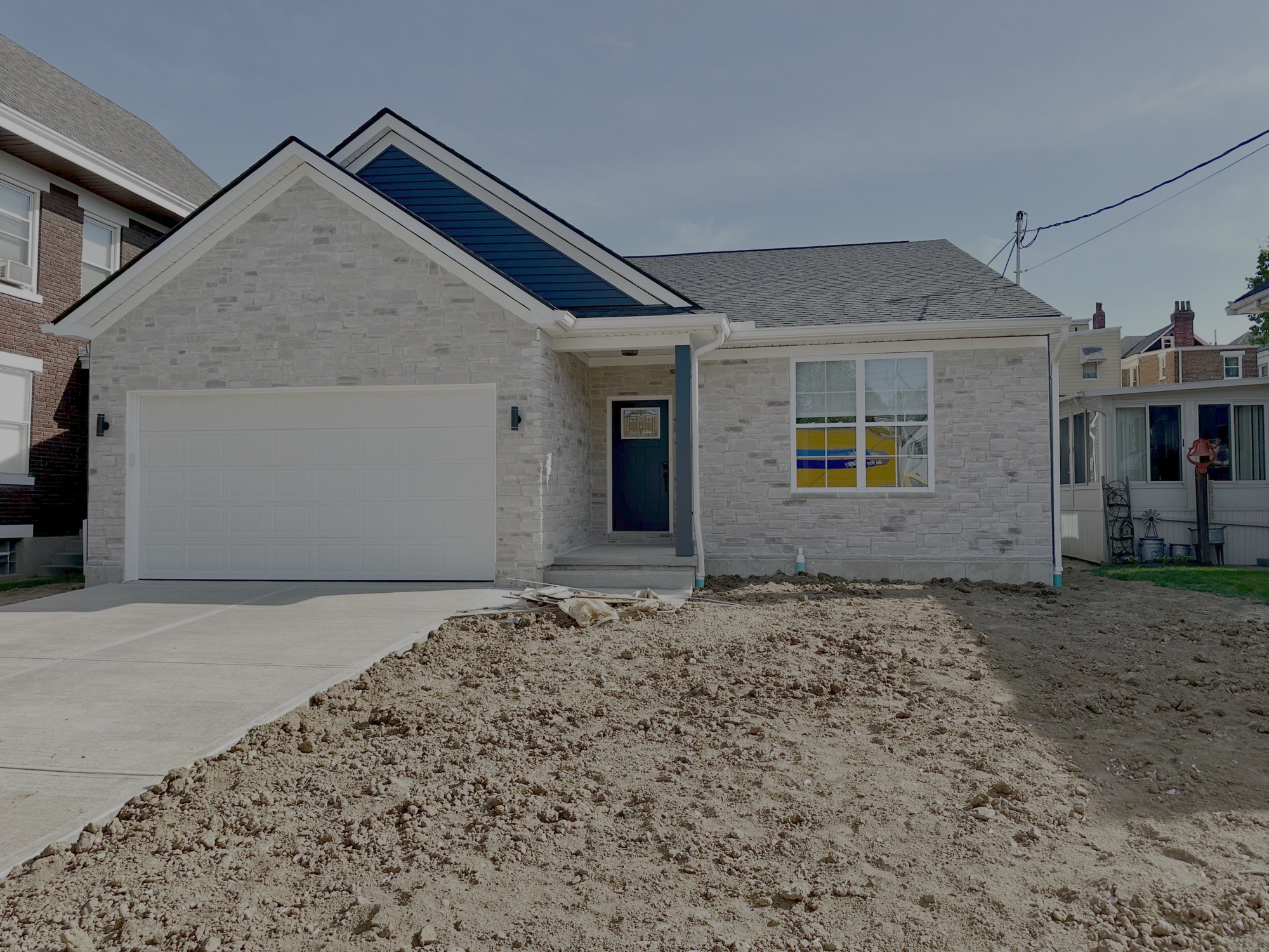 After: the new single-story stone home with a two-car garage, built on the same lot