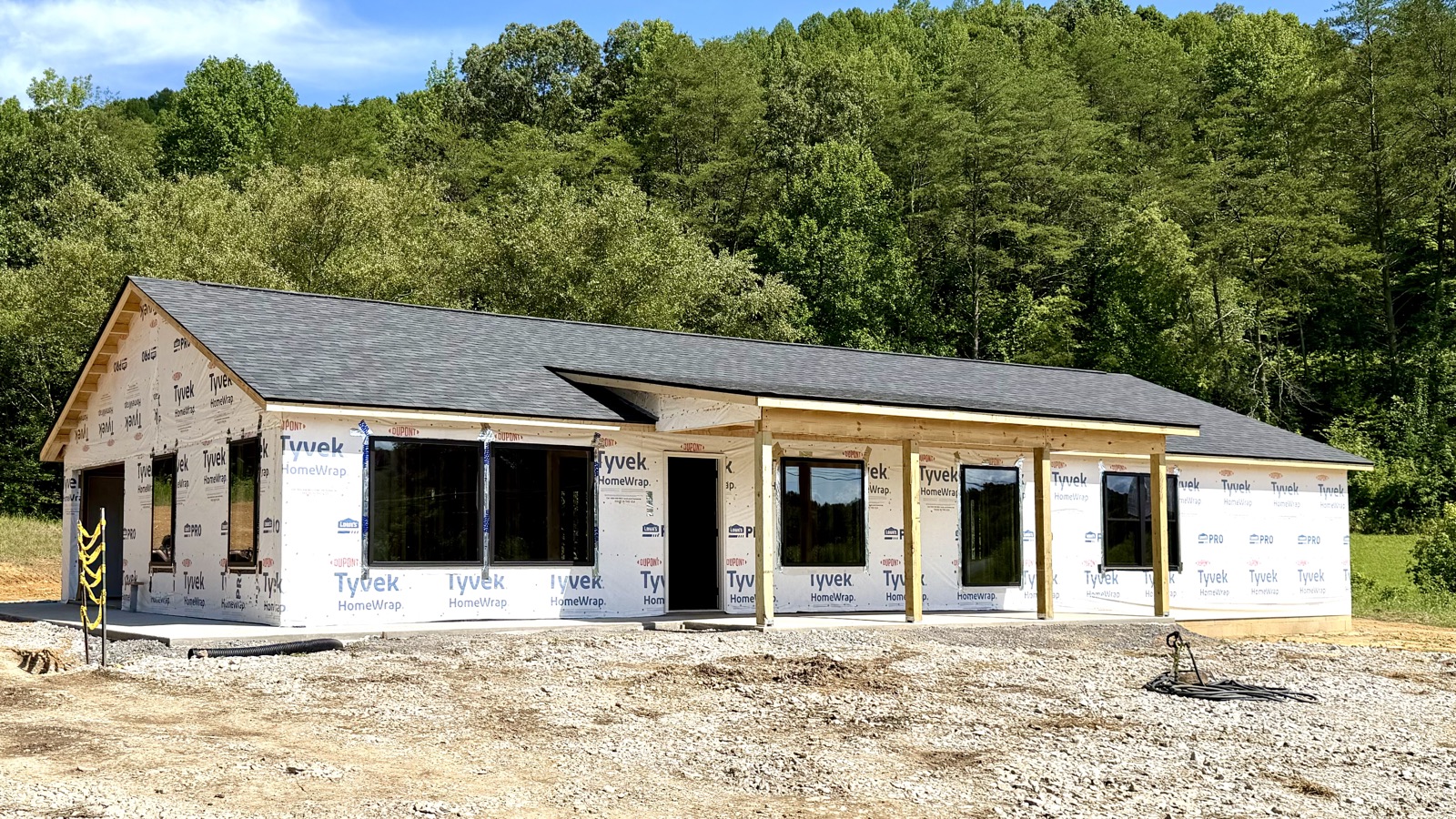 After: the same single-story house with a shingled roof, house wrap, windows and a covered front porch