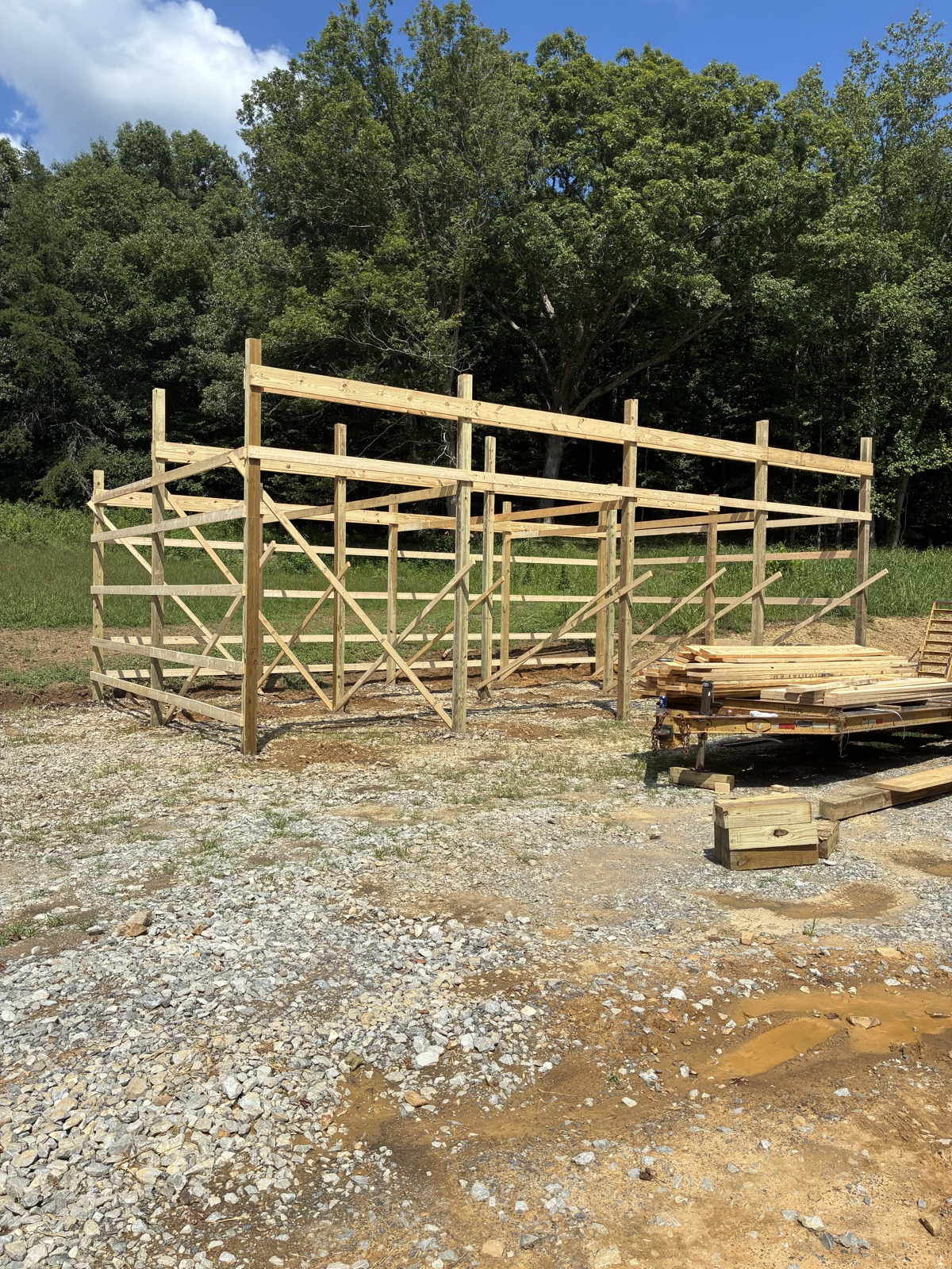 The wood post-and-girt framing of a new barn on a gravel pad