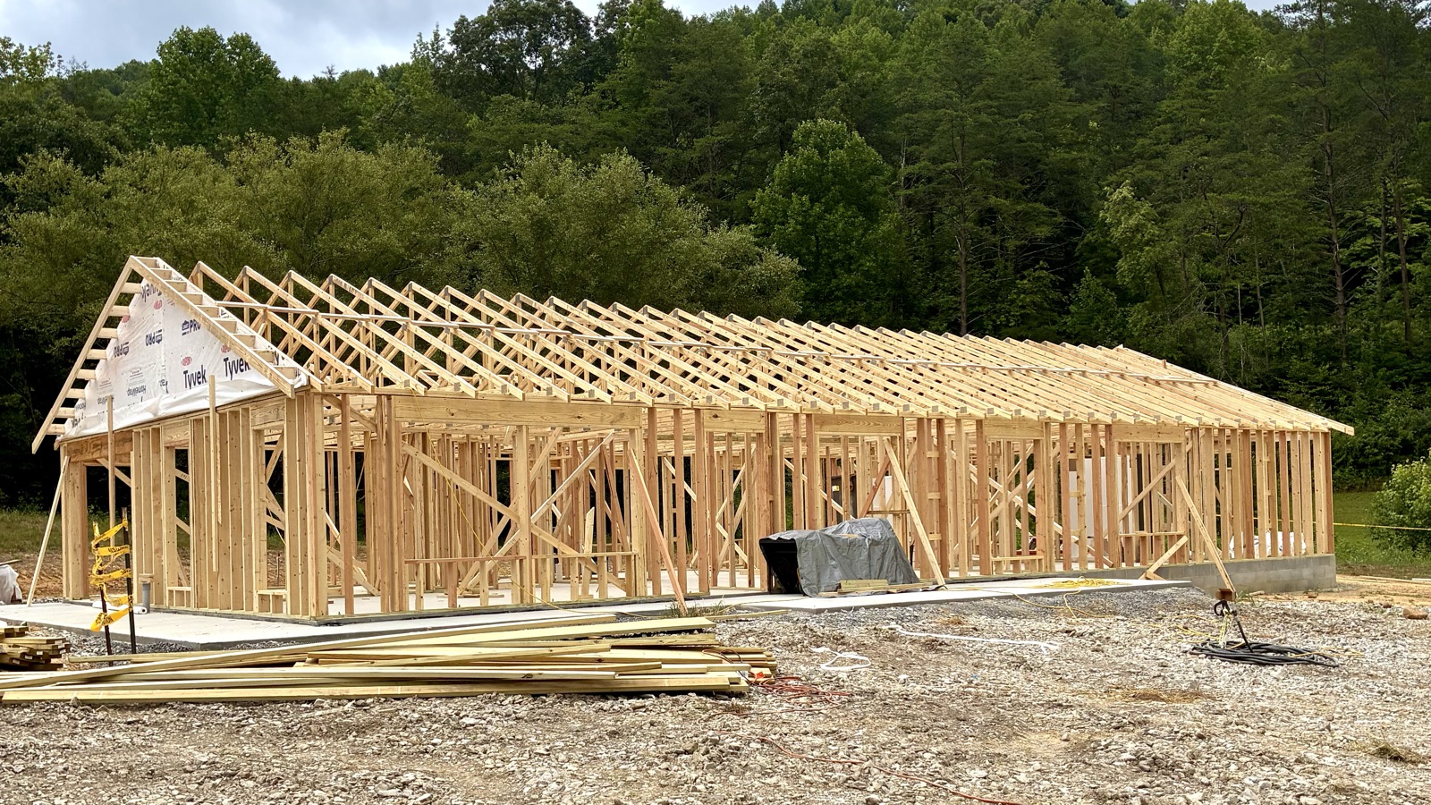 Before: the bare wood wall framing and roof trusses of a long single-story house