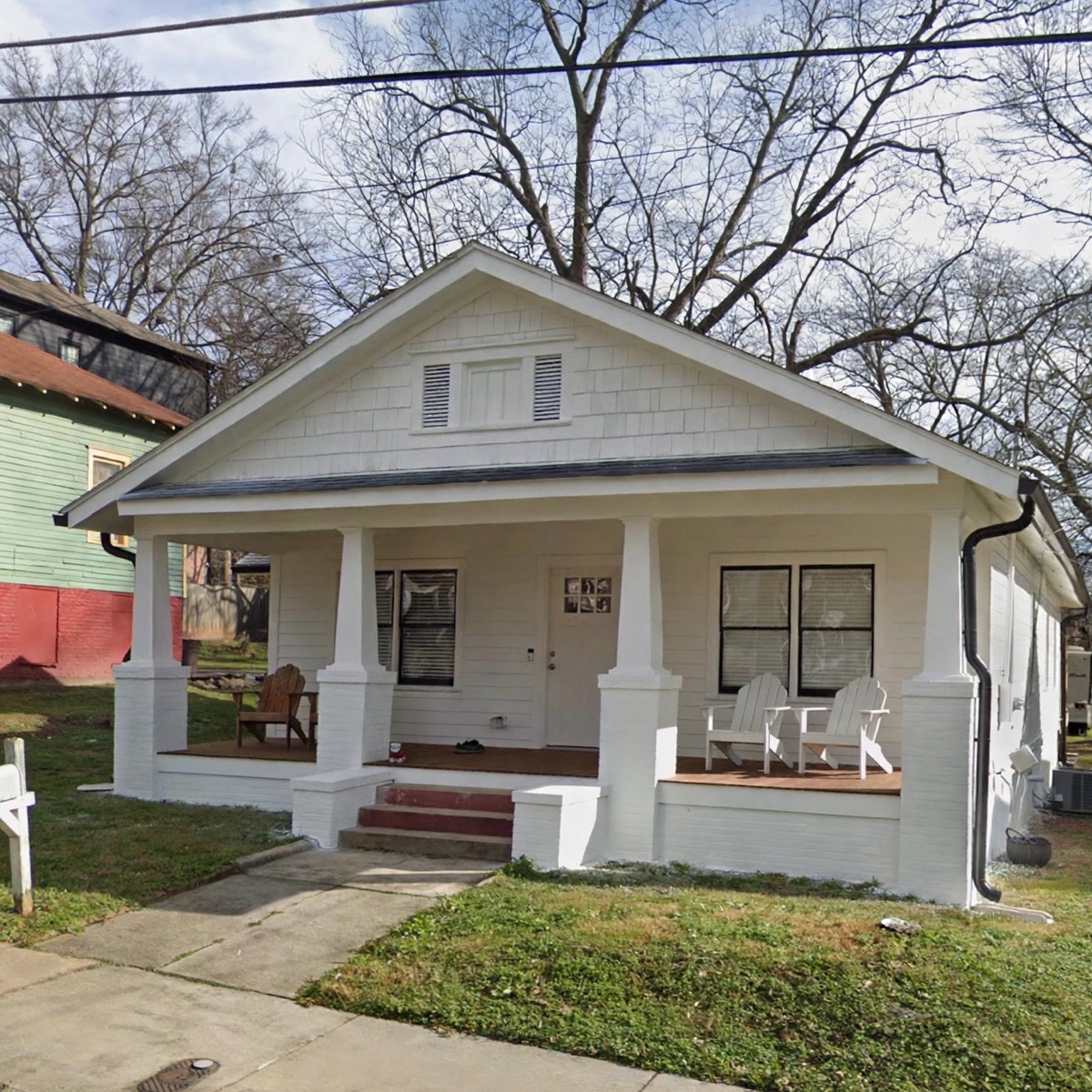 Before: a white bungalow with plain grass up to the porch and no planting beds
