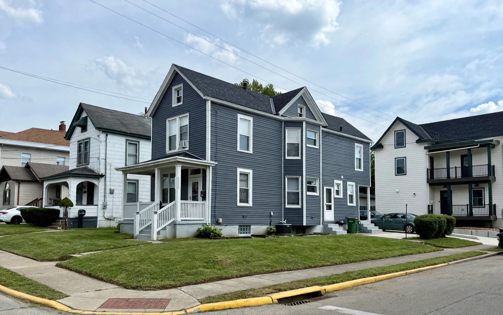 A freshly mowed and edged corner lawn in front of a blue two-story house