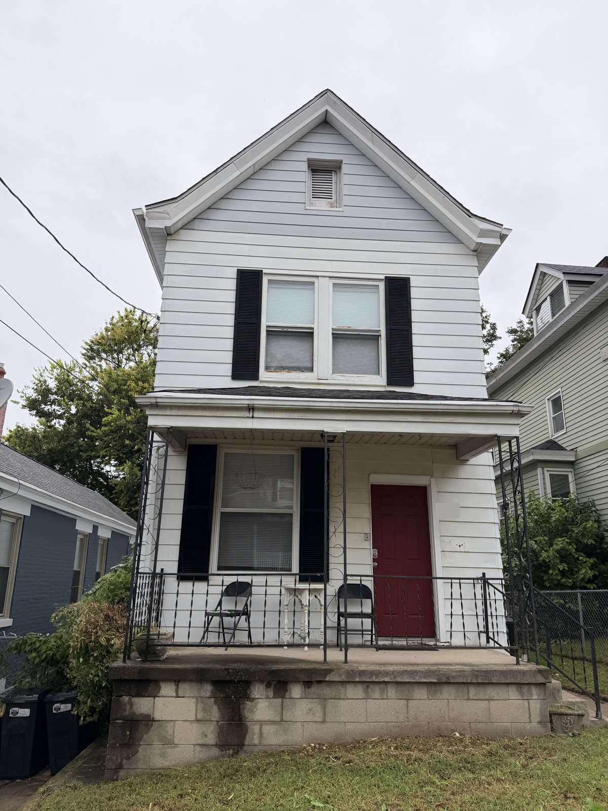 A white two-story house with black shutters and a red front door