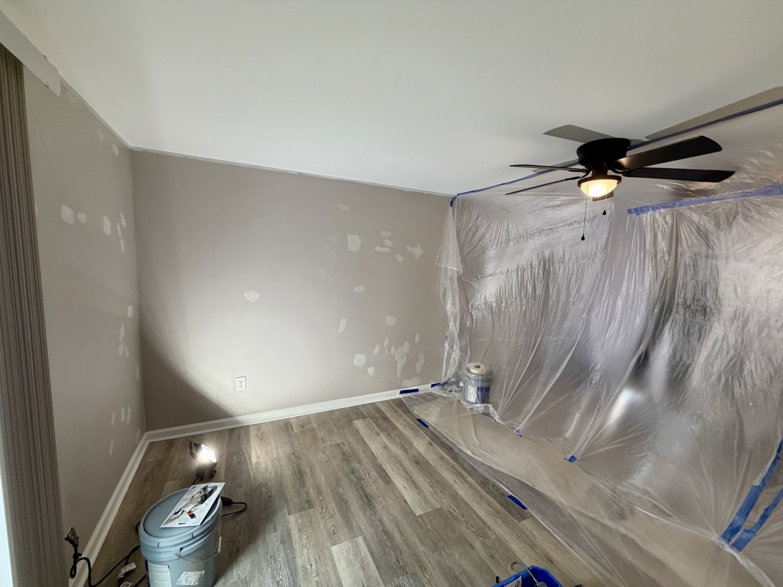 An apartment bedroom with patched walls and plastic sheeting, ready for paint