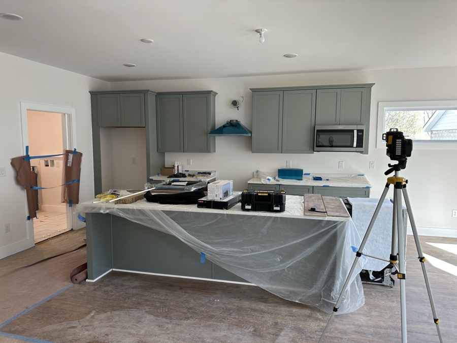 A kitchen island covered in plastic and masked off before painting