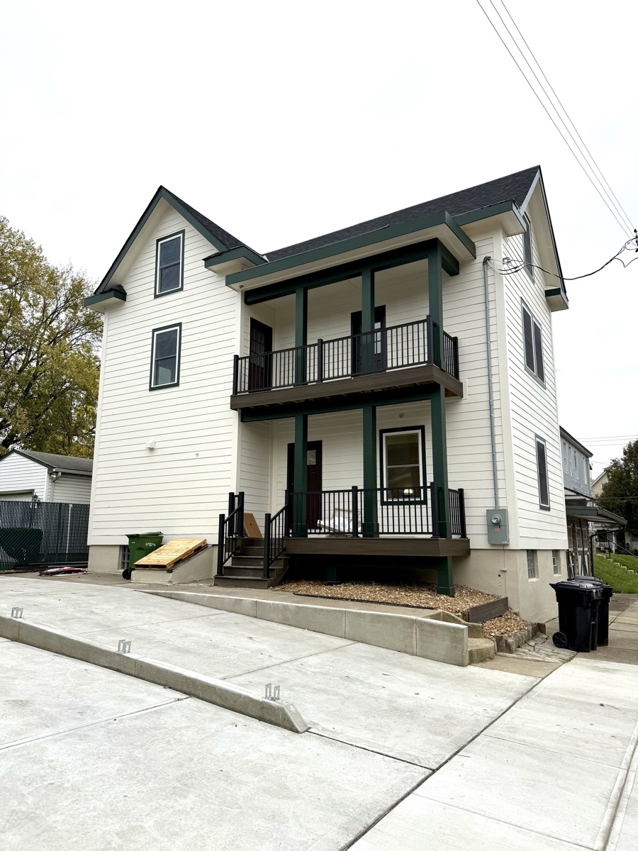 A freshly painted white two-story house with green trim and a two-story porch