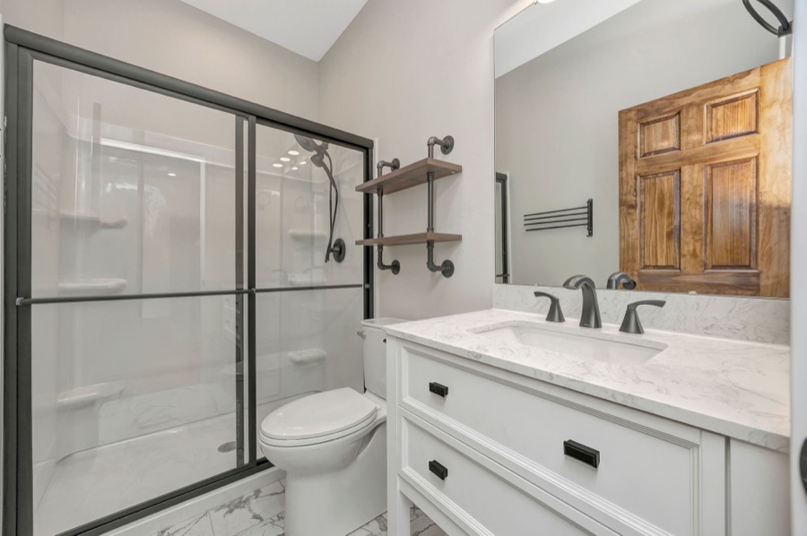 A renovated bathroom with a glass shower and white vanity
