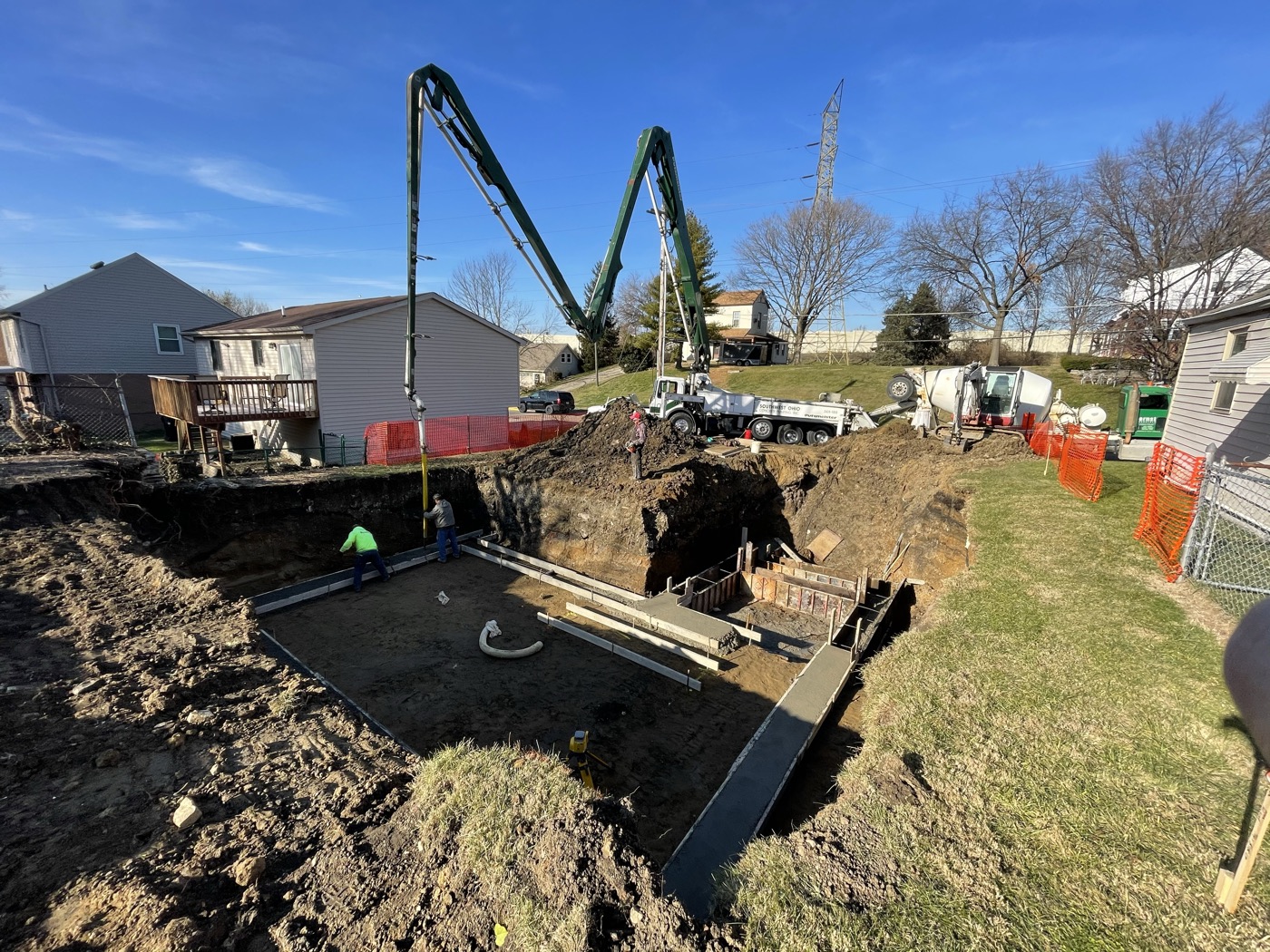 A concrete pump truck reaching into an excavated lot