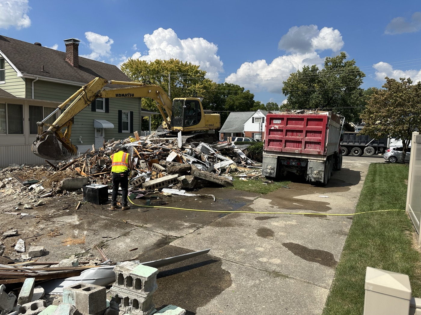 A crew and dump truck hauling demolition debris off a lot