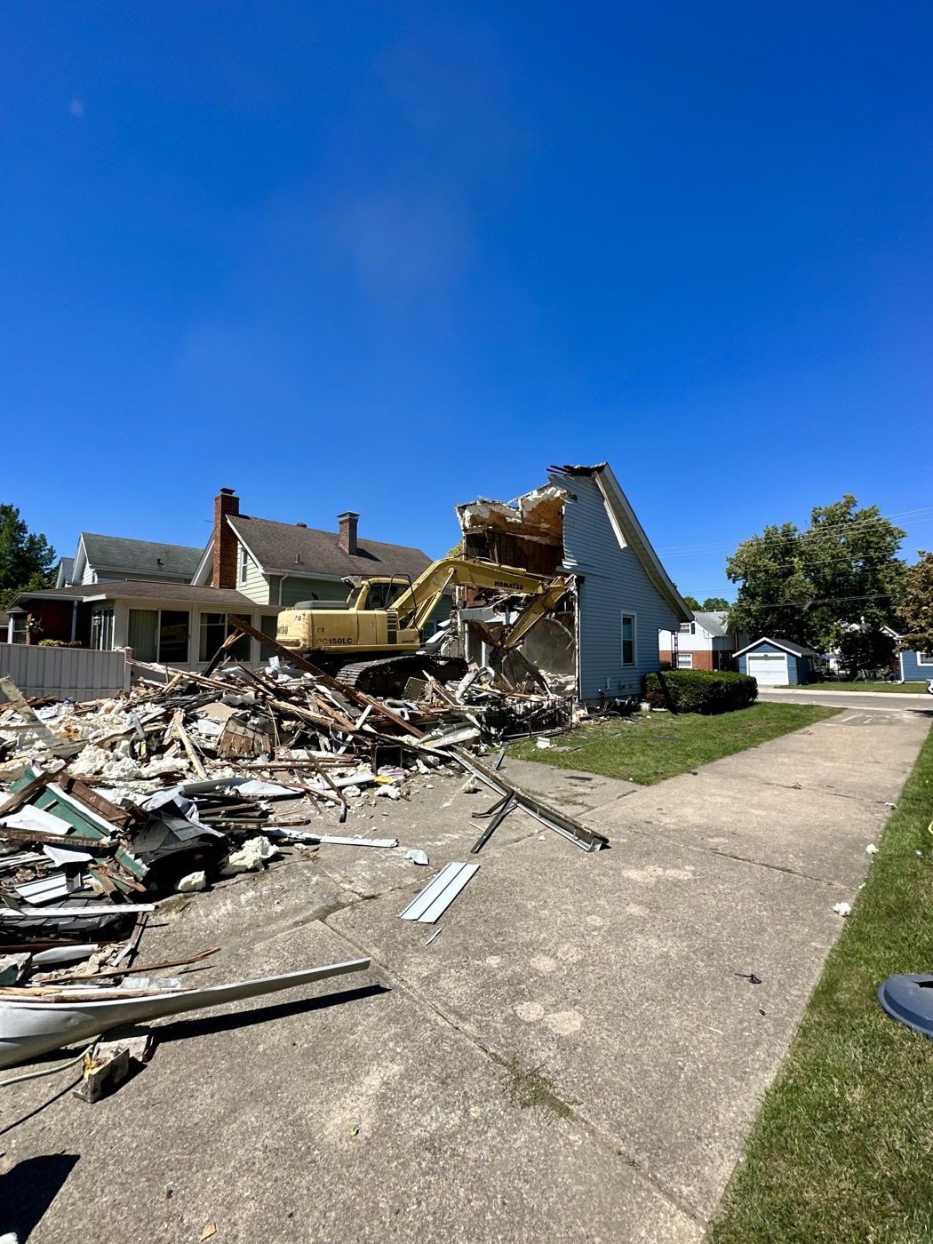 An excavator clearing demolition debris from a lot