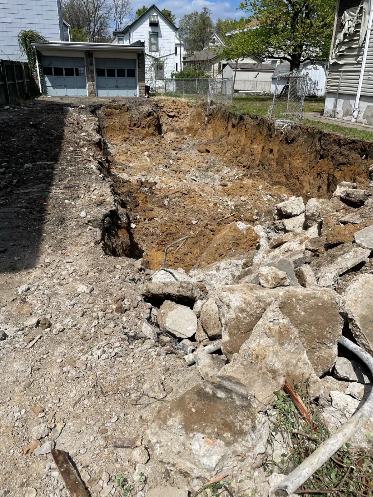 The old basement dug out, with broken foundation concrete piled to the side