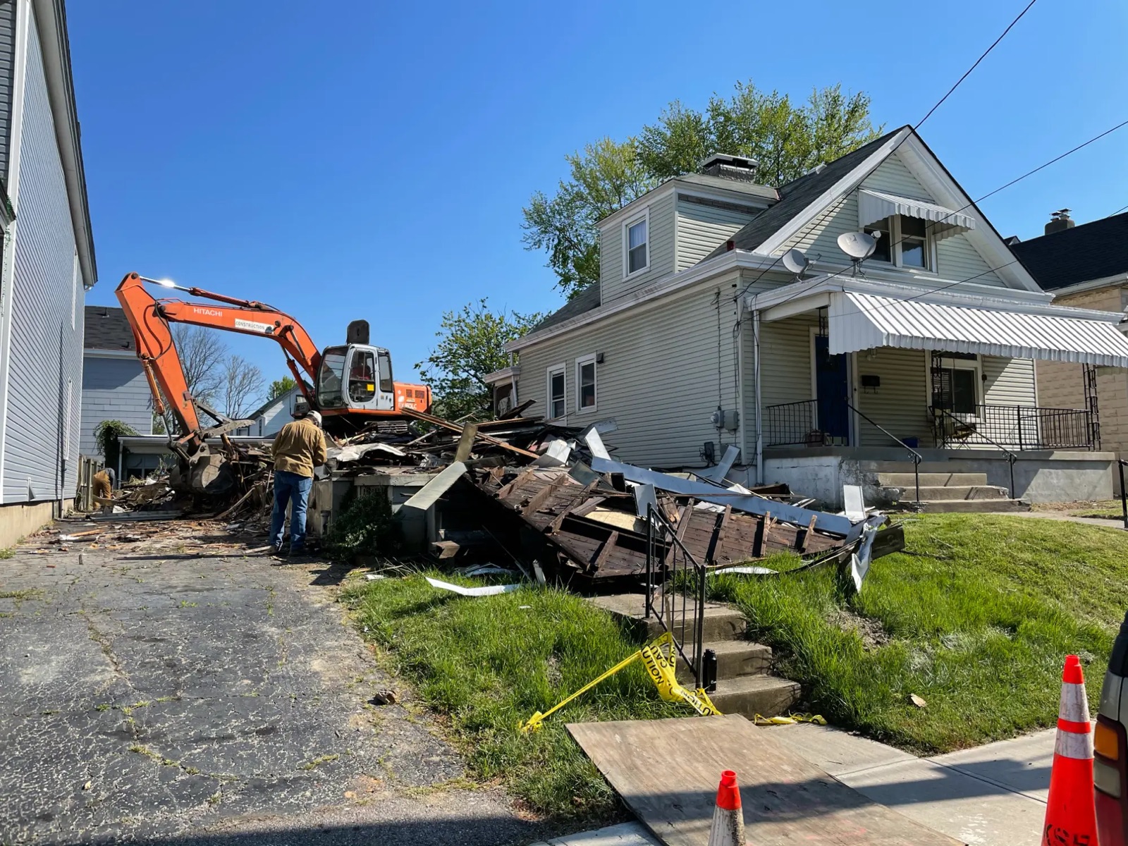 The house knocked down into a debris pile beside the neighboring home