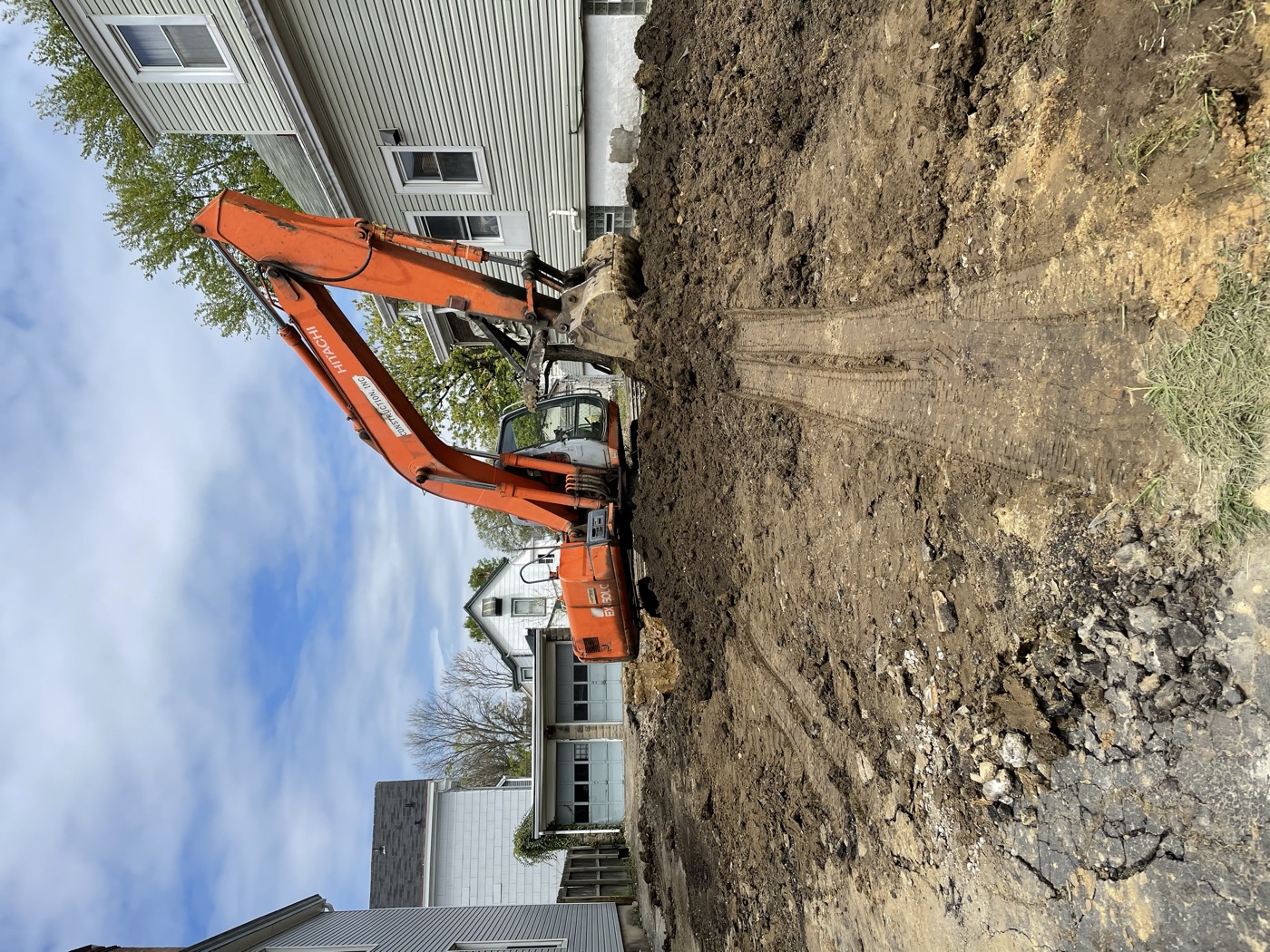An excavator digging out a lot between houses