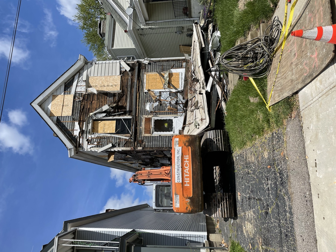 An excavator tearing down an old two-story house
