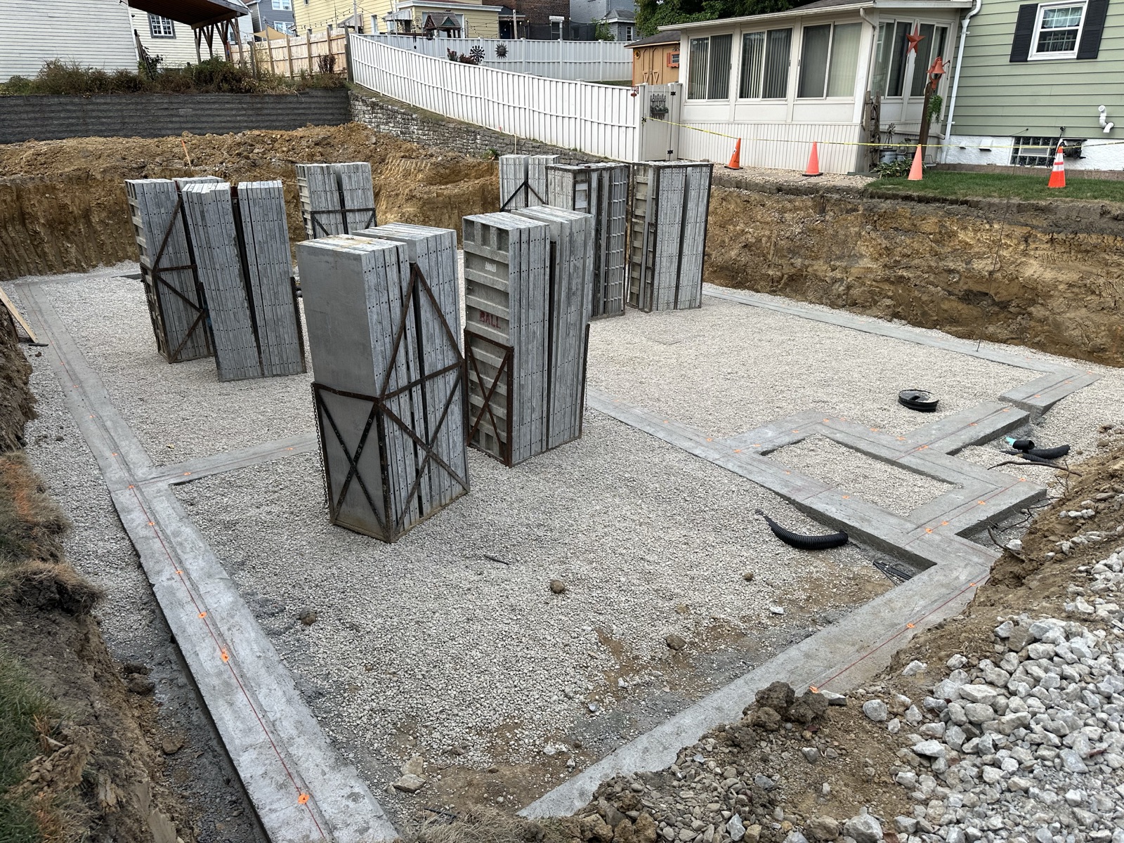 Stacks of foundation wall forms staged on the finished footings and gravel