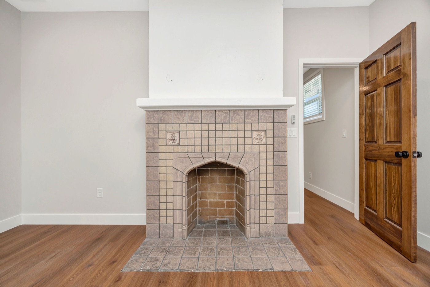 A living room with a tiled fireplace and wood floors