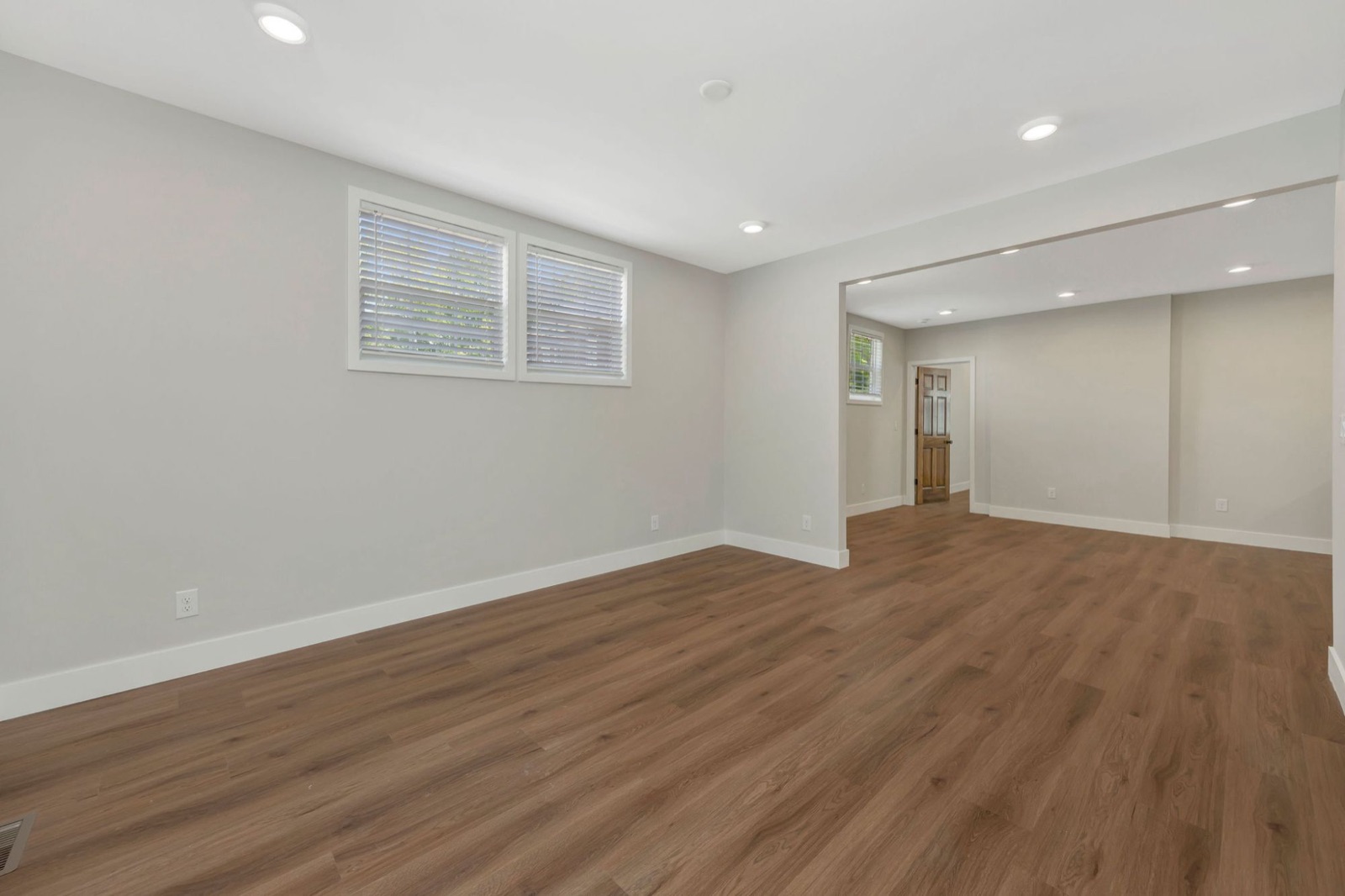 A finished lower level with wood-look floors, recessed lights and wide openings between rooms