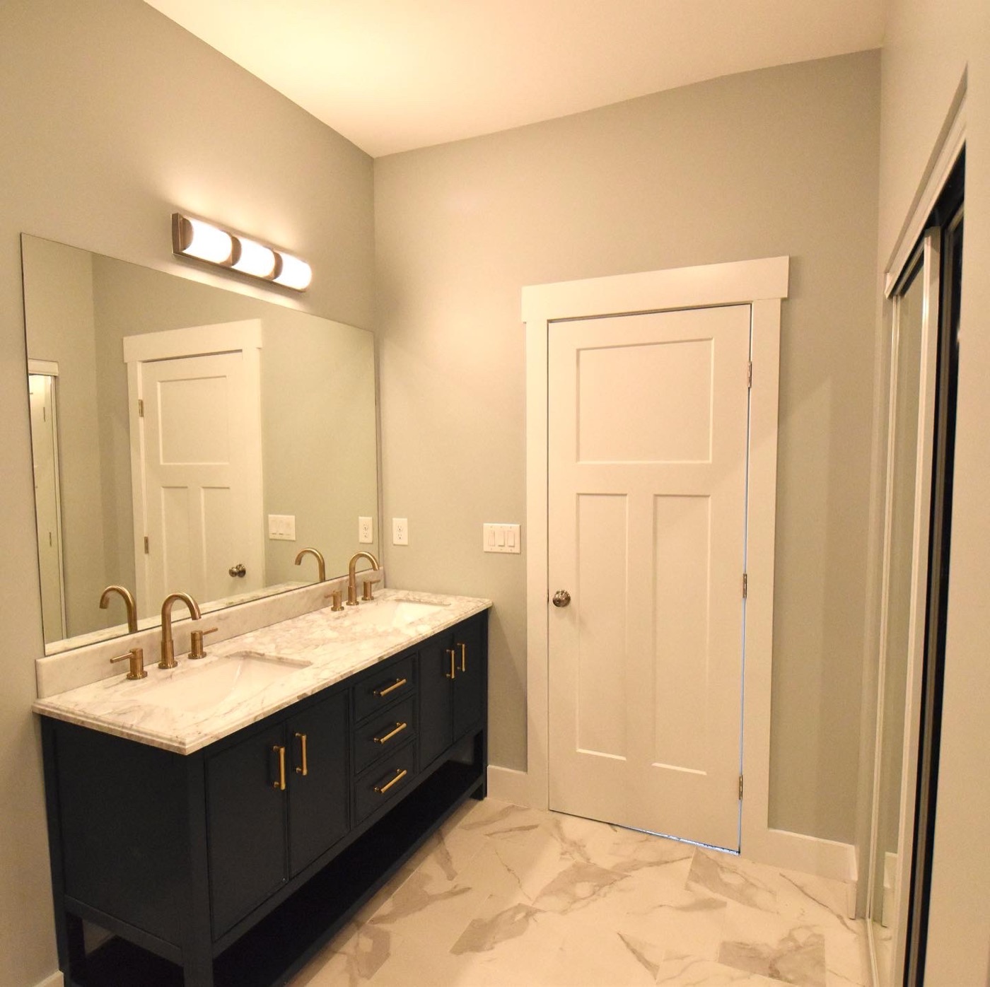 A remodeled bathroom with a dark vanity and wall lights