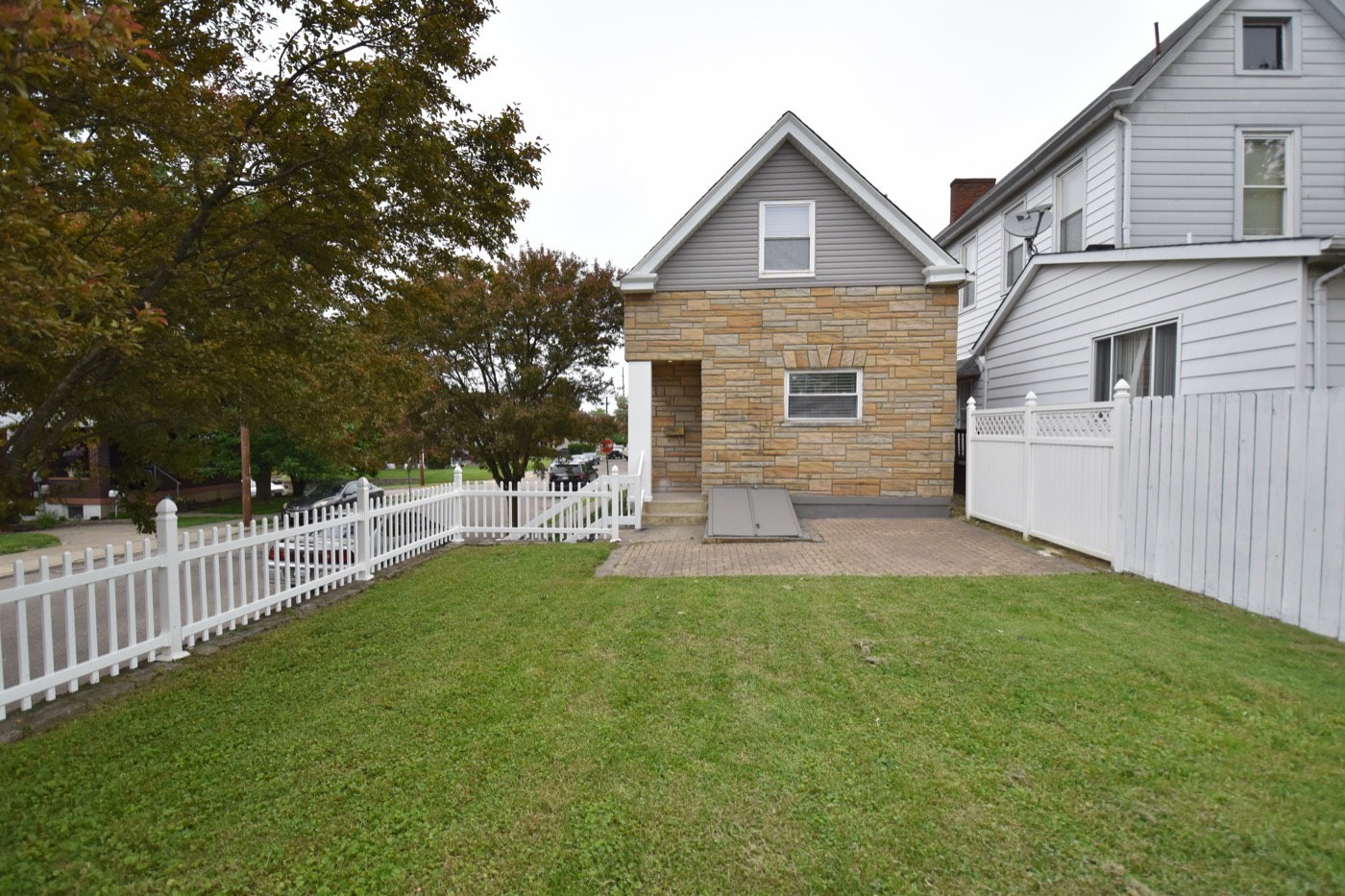 A remodeled stone-front cottage with a new fence and lawn