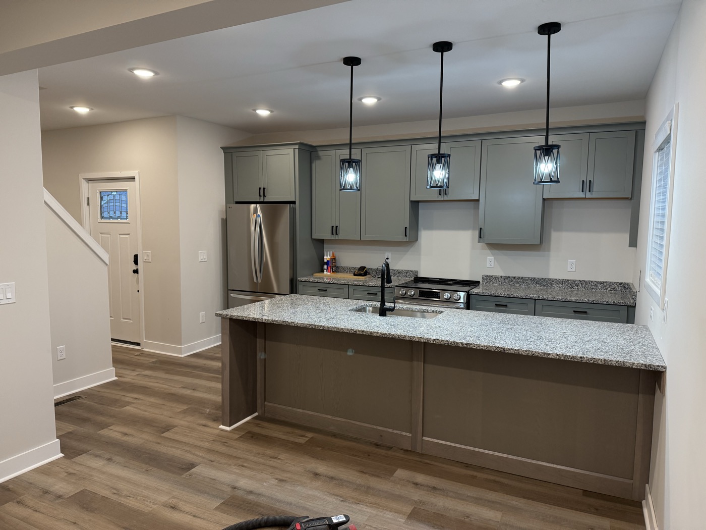 A remodeled kitchen with a large island and pendant lights