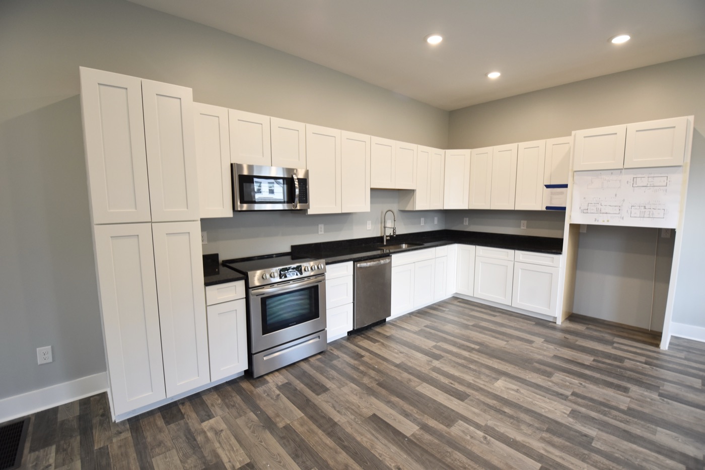 A remodeled kitchen with white cabinets and stainless appliances