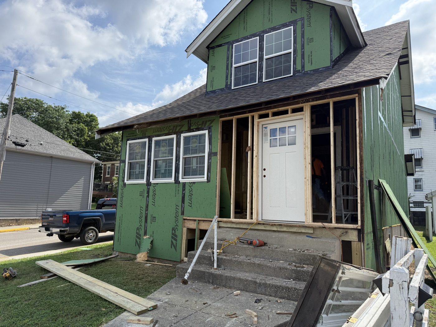 A two-story house wrapped in green sheathing with new windows going in